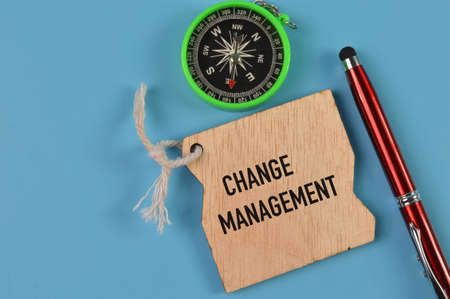 Top view of pen, compass and wooden board written with CHANGE MANAGEMENT
