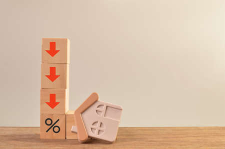 Toy house and red arrow pointing down. House market crash conceptの写真素材