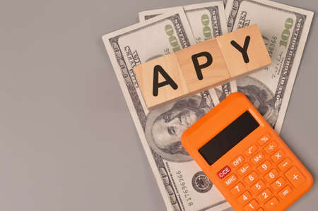 Top view of money banknotes, calculator and wooden blocks written with APY stands for ANNUAL...