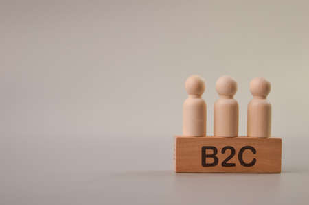 Wooden people figures standing on wooden block written with B2C stands for Business To Customer