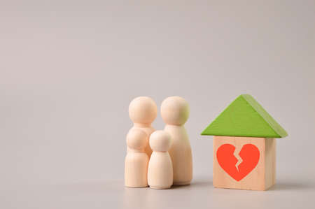 Wooden doll figures, toy house and broken heart symbol. Concept of divorce, family split and crack in relationships.の写真素材