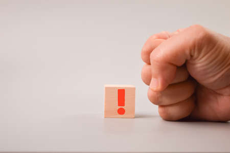 Man hand and wooden block drawn with exclamation mark symbolの写真素材