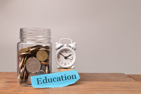 Clock, stack of coins and torn paper written with EDUCATION