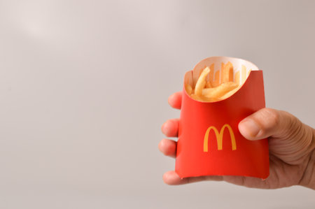 Klang, Malaysia: June 24, 2021- Hand holding McDonald's french fries in paper cup. McDonald's is a fast food restaurant chainのeditorial素材