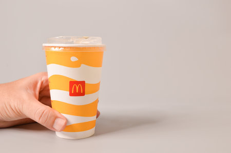 Klang, Malaysia: June 24, 2021- Hand holding McDonald's soft drink in paper cup isolated on grey background. Copy space.のeditorial素材