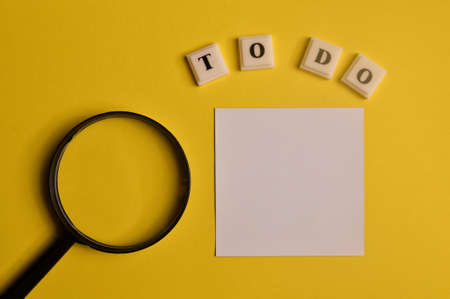 A magnifying glass, memo note and square letters with text TO DO. Copy space