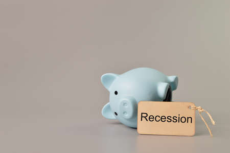 Piggy bank and label tag written with RECESSION. Global crisis concept.の写真素材