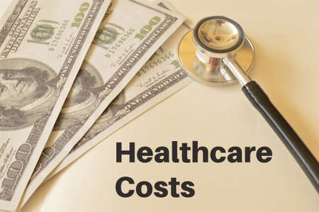 Stethoscope and money banknotes with text HEALTHCARE COSTS.の写真素材