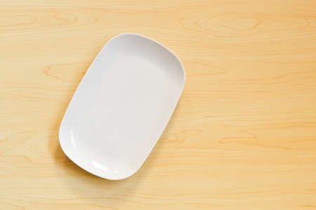 Top view of empty white plate on the wooden tableの写真素材