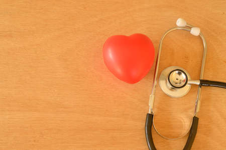 Stethoscope and red heart shape on wooden background. Health concept