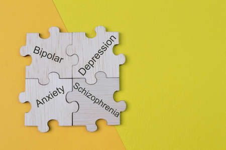 Wooden jigsaw puzzle with text BIPOLAR, ANXIETY. DEPRESSION and SCHIZOPHRENIA