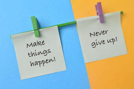 Paper notes with phrase MAKE THINGS HAPPEN! and NEVER GIVE UP!の写真素材