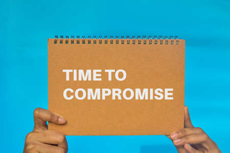 Hand holding book written with phrase TIME TO COMPROMISEの写真素材
