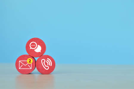 Red wooden block with email, chat and telephone symbols. Communication and customer service conceptの写真素材