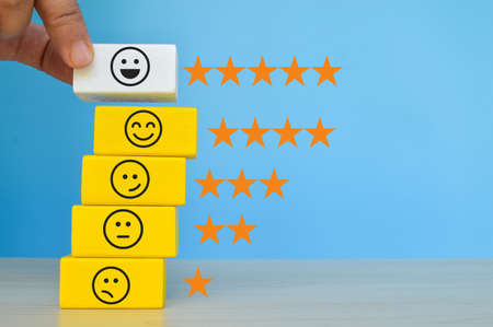 Wooden cube blocks with different face emotions. Customer evaluation and satisfaction concept.