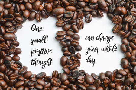 Roasted coffee beans isolated on a white background with text ONE SMALL POSITIVE THOUGHT CAN CHANGE YOUR WHOLE DAYの写真素材