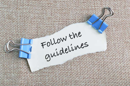 Top view of torn paper written with text FOLLOW THE GUIDELINES.の写真素材