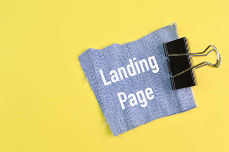 Ripped pieces of jeans with text LANDING PAGE isolated on a yellow backgroundの写真素材