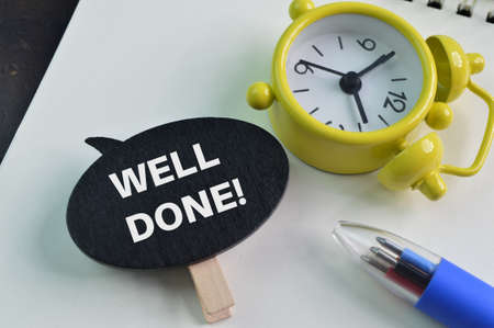 Pen, clock and wooden speech bubble with text WELL DONEの写真素材