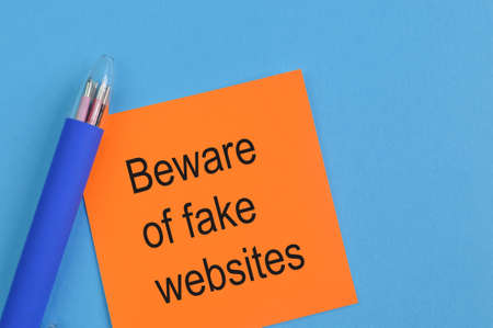 Pen and memo note written with text BEWARE OF FAKE WEBSITESの写真素材