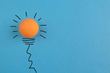 Great idea concept with light bulb table tennis ball isolated on a blue backgroundの写真素材