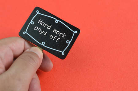 Hand holding wooden board written with text HARD WORK PAYS OFFの写真素材