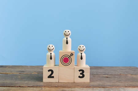 Wooden doll figures standing on the podiums. The concept of victory and business competition
