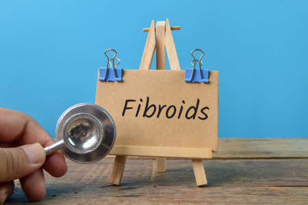 Stethoscope and brown card written with FIBROIDS. Health concept