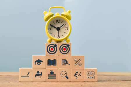 Yellow clock and wooden block with education icons, Strive for success concept