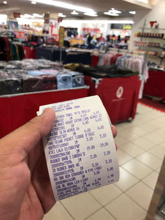 Selangor,Malaysia: November 15, 2021- Hand holding paper sales receipt with blurred backgroundのeditorial素材