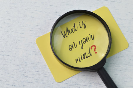 Magnifying glass and yellow card with question WHAT IS ON YOUR MIND?の写真素材
