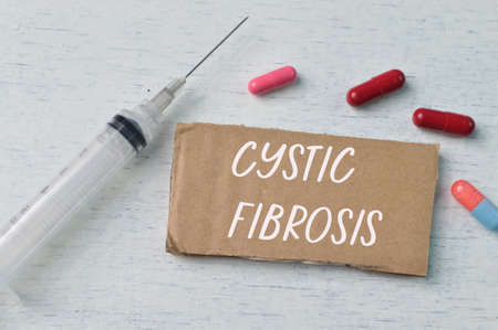 Syringe injection, pill capsules and brown card with text CYSTIC FIBROSISの写真素材