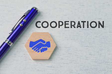 Cooperation word, pen and jigsaw puzzle with handshake symbolの写真素材