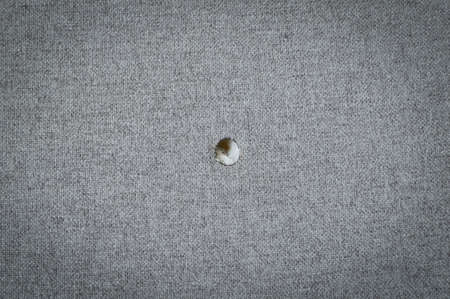 Cotton fabric with a hole from a cigarette