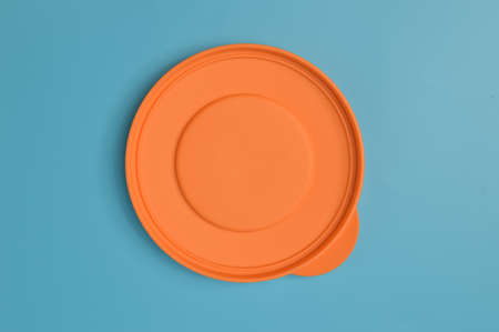 An orange plastic lid isolated on a blue backgroundの写真素材