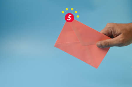 Hand holding peach envelopes with email notification symbolの写真素材
