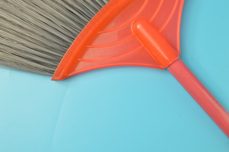 Close up view of red black plastic broom isolated on a blue background