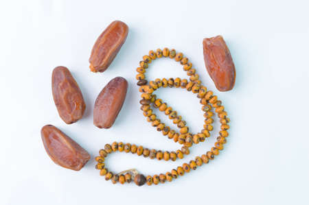 Top view of dried dates or kurma and prayer beads isolated on a white background