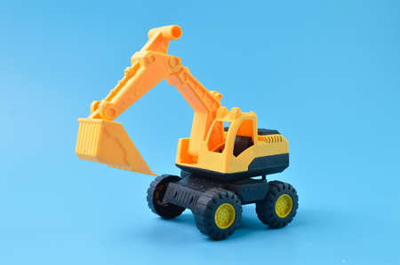 Construction plastic backhoe tractor toy isolated on a blue backgroundの写真素材