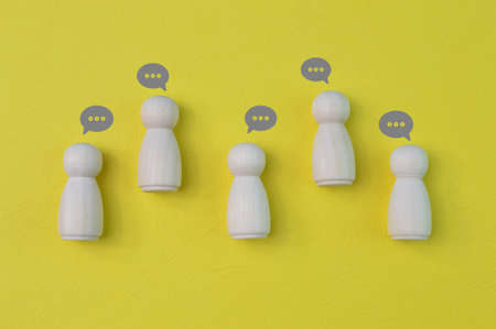 Wooden doll people figures with comment clouds. Cooperation, collaboration and communication in...