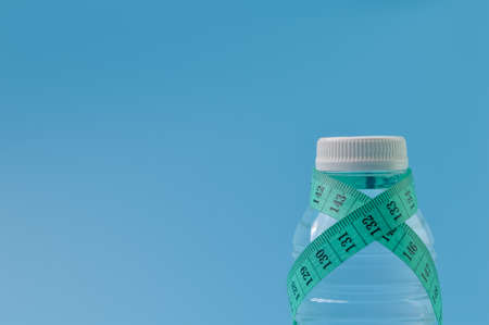tape measure and mineral water bottle isolated on a blue backgroundの写真素材