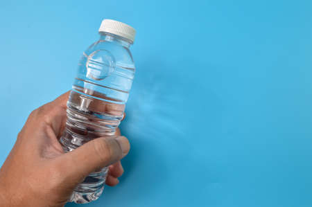 Hand holding mineral water isolated on a blue background