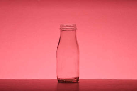 White glass bottle isolated on a red background