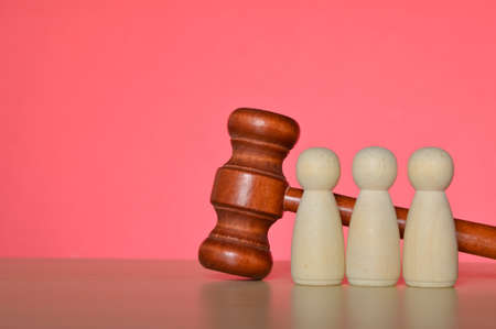 Wooden doll figures and judge gavel isolated on a red background. Legal law and justice concept.の写真素材