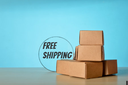 Cardboard boxes and magnifying glass with text FREE SHIPPINGの写真素材