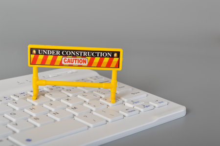 Laptop keyboard and under construction sign. Website maintenance, programming, repair, coding and under maintenance concept.の写真素材