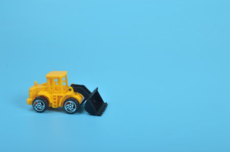 Yellow backhoe loader isolated on a blue background. Copy space for the text.