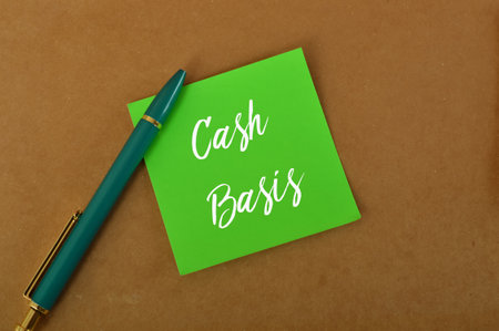 Green pen and green paper written with CASH BASIS. Concept meaning fixed regular payment typically...