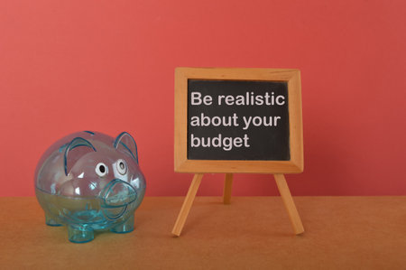 Piggy bank and blackboard written with BE REALISTIC ABOUT YOUR BUDGET.の写真素材