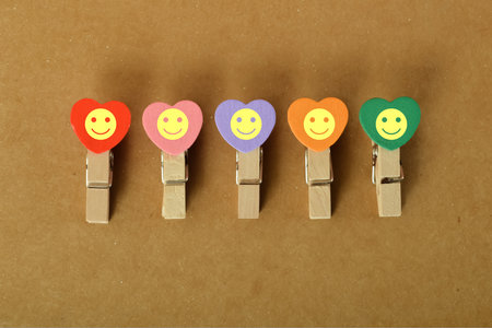 The happy face symbol on brown background depicted by clothespins conveys the concept of evaluating and improving customer experience, satisfaction, and excellent services rating, with sufficient copy space.の写真素材